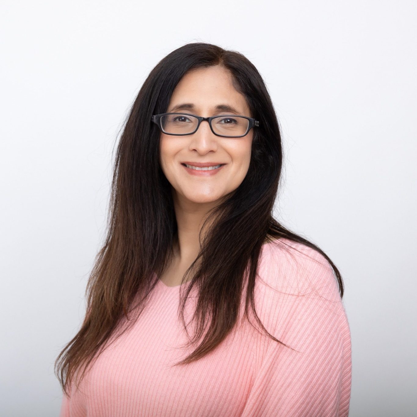 Tanya Lanwarne A woman with long, dark hair smiles against a pink background.
