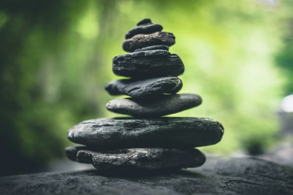 Stack of smooth stones in balanced formation against a blurred green background.